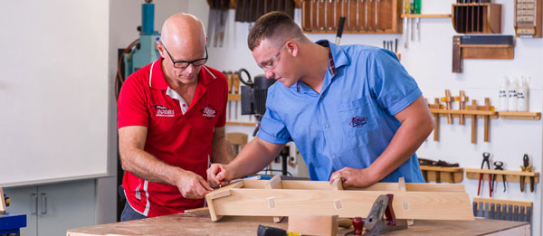 Student and teacher in a workshop doing some wood work.