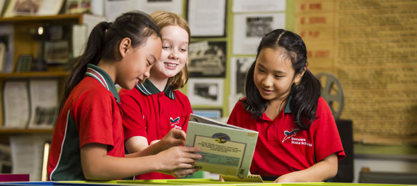 Three primary school students enjoying a book