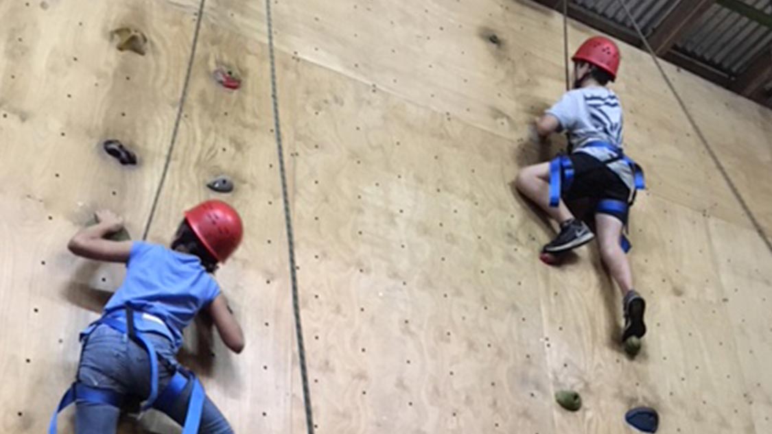 Two students using an indoor rock climbing wall