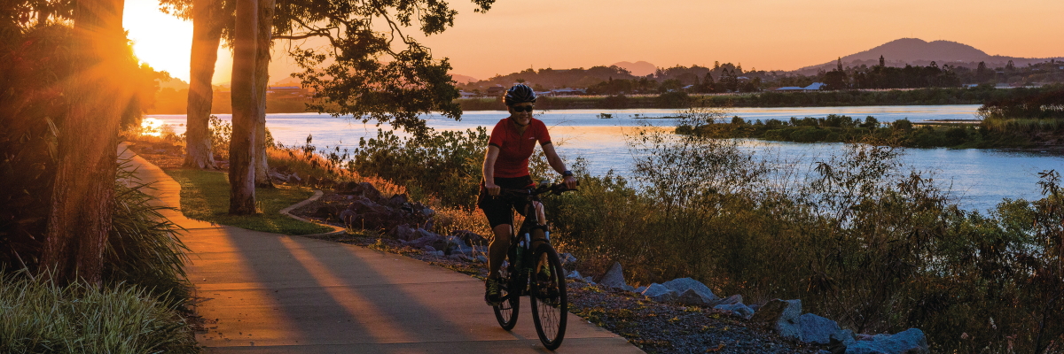 Person riding a bike on a path while the sun sets